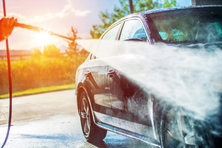 Auto wird mit einem Dampfstrahler behandelt, idyllisches Bild, Sonnenuntergang im Hintergrund